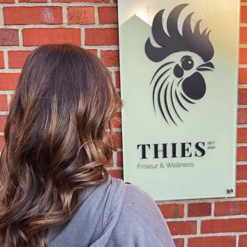 Braunes Haar mit hellen Strähnen und Locken vor dem Thies-Schild